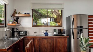 Une cuisine moderne avec des meubles en bois, des appareils électroménagers en acier inoxydable et une fenêtre donnant sur un espace verdoyant.