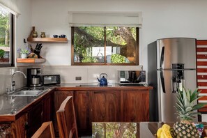Une cuisine moderne avec des meubles en bois, des appareils électroménagers en acier inoxydable et une fenêtre donnant sur un espace verdoyant.