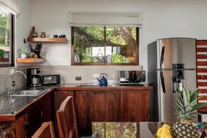 Una cocina moderna con armarios de madera, electrodomésticos de acero inoxidable y una ventana con vistas a zonas verdes.