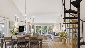 A spacious living area with a dining table, chairs, a sofa, and a staircase. - Relax in Sea Pines | Bikes to Beach, Golf & Family Fun Included (Hilton Head Island)