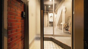 An interior view of a hotel lobby with a red brick wall, a glass door, and a tiled floor.