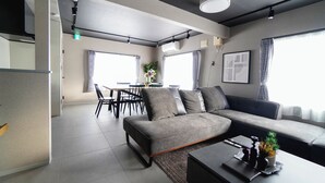 A modern living room with a grey sectional sofa, a coffee table, and a dining area with a table and chairs.