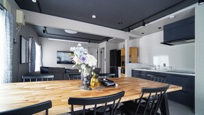 A modern kitchen with a wooden dining table, black chairs, and a vase of flowers.