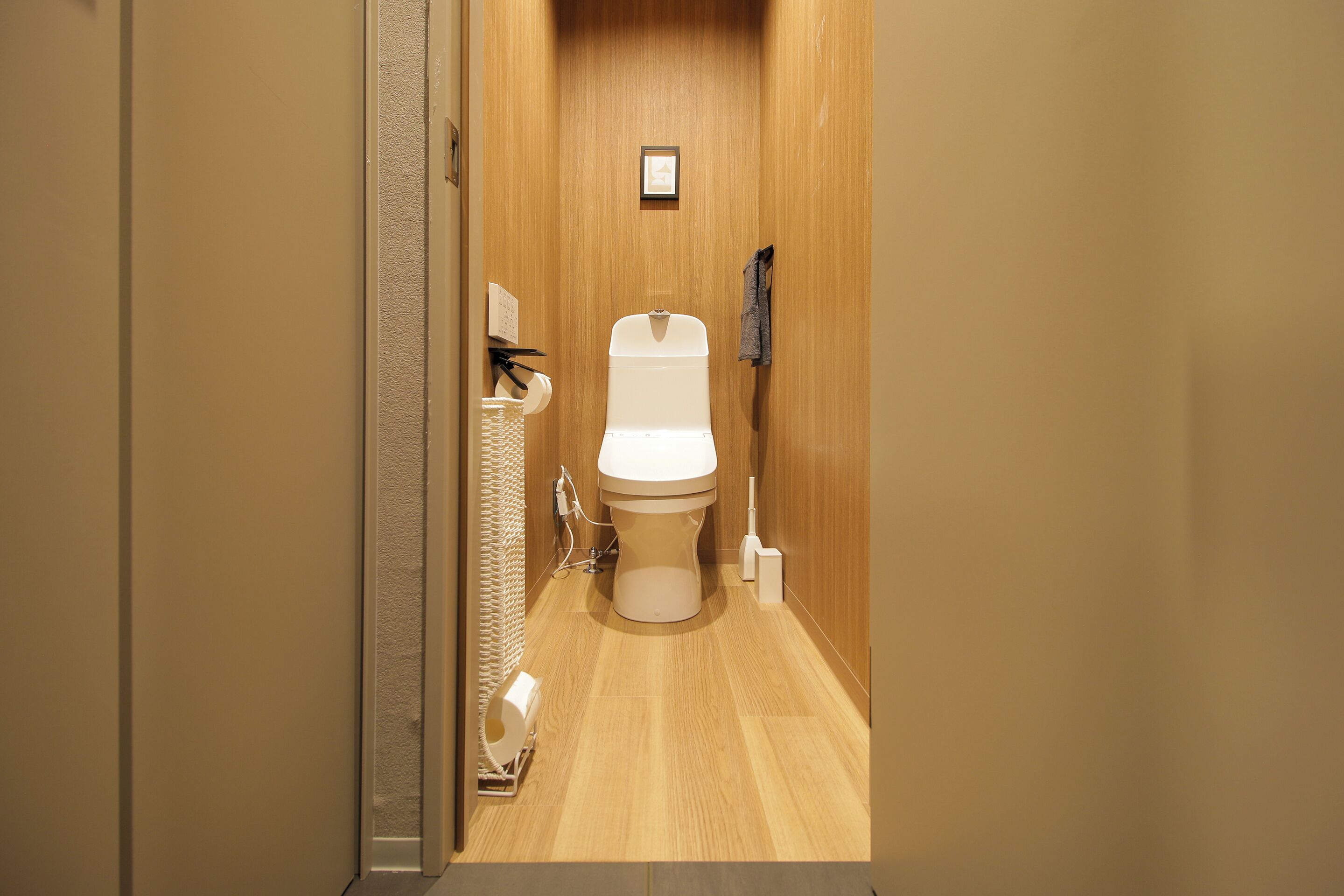 A compact, modern bathroom with a wooden vanity, a toilet, and a towel rack.