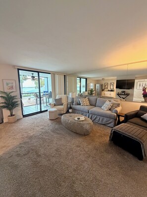 Ein modernes Wohnzimmer mit einer großen Couch, einem Couchtisch und Blick ins Freie.