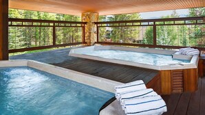 Ein Whirlpoolbereich mit Holzterrasse, Steinpfeiler und Blick auf Grünflächen.