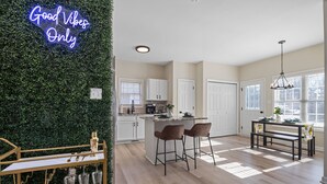 Una cocina moderna con barra, un letrero de neón y un comedor con banco.