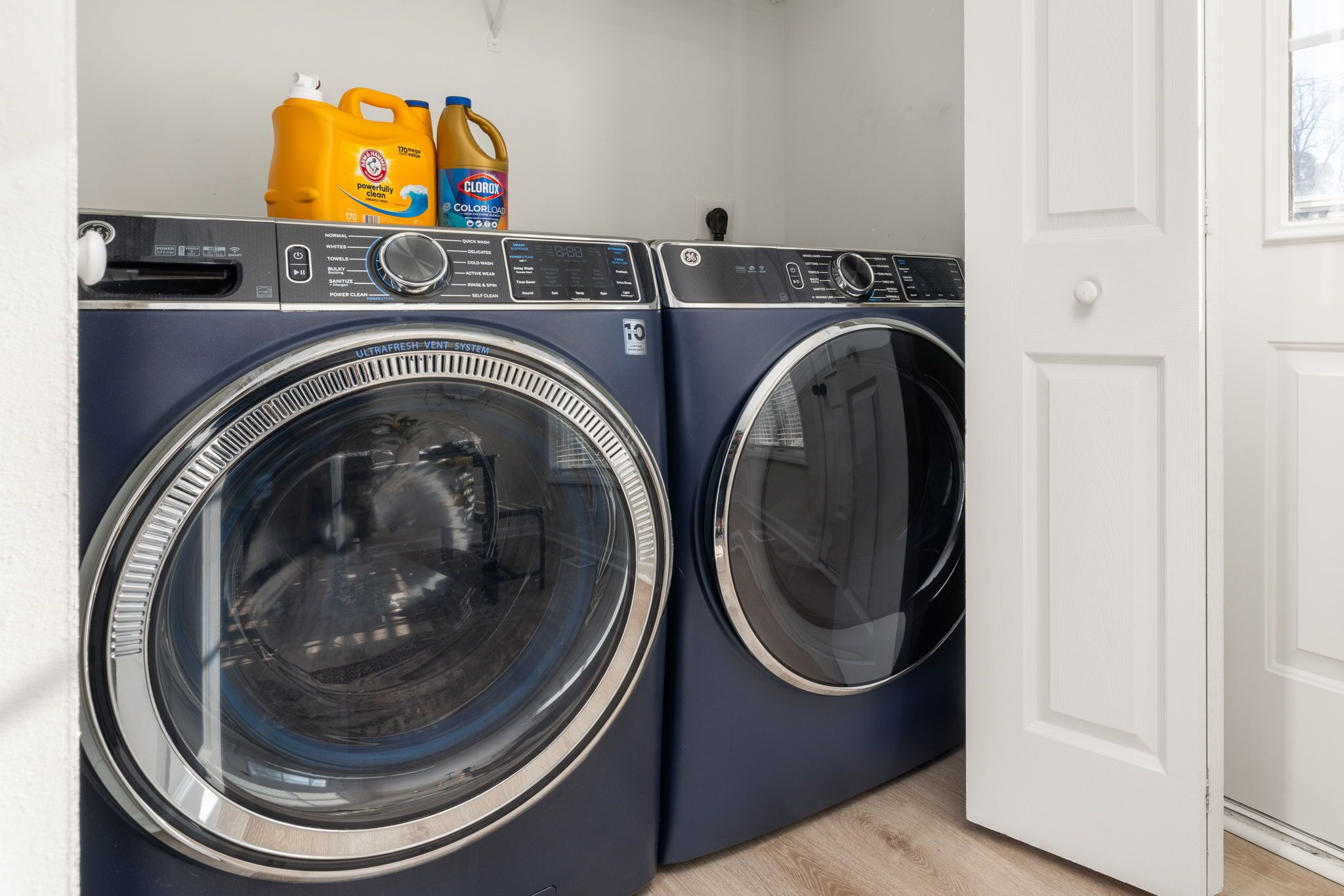A laundry area with two front-loading washing machines and detergent bottles on top.