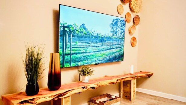 Un televisor montado en la pared con un banco de madera rústico debajo.