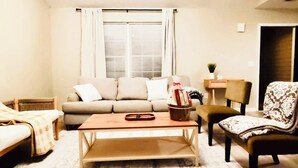 Una sala de estar acogedora con un sofá, una mesa de centro y un sillón estampado.