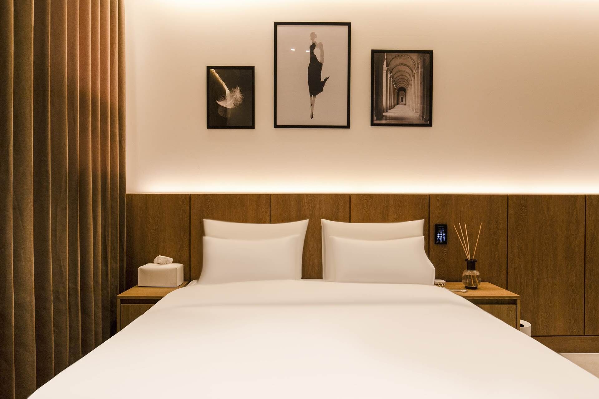 Una camera d'albergo con un letto grande, due comodini e tre quadri appesi al muro.