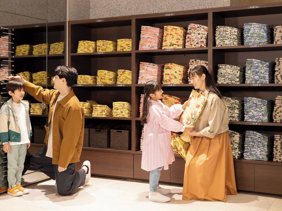 A clothing store with shelves of folded fabrics and a mirror reflecting the interior.