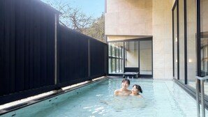 A swimming pool with a black fence, a modern building with large windows, and a clear sky. - Ooedo Onsen Monogatari Premium Sendai Sakunami (Sendai)