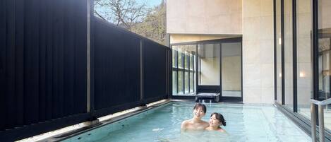 A swimming pool with a black fence, a modern building with large windows, and a clear sky.