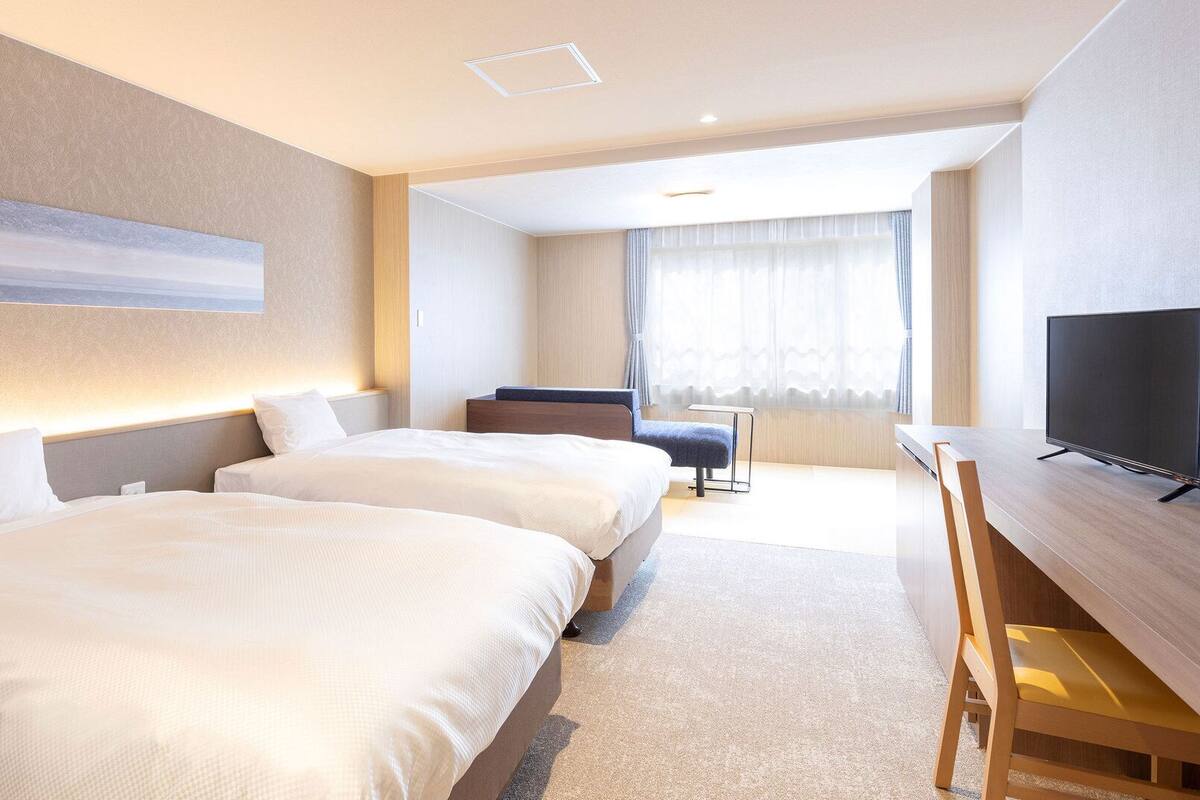 Une chambre d’hôtel avec deux lits, une télévision, un bureau et une chaise.