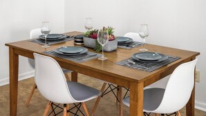 Una mesa de comedor dispuesta con platos, vasos y un centro de mesa.