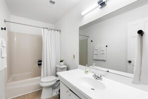 Een moderne badkamer met een bad, toilet en wastafel.
