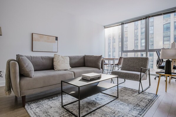 Relax in a stylish living space with a sofa, armchair, and city view.