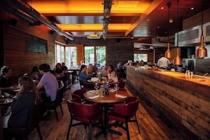 A restaurant with wooden walls, round tables, and red chairs. - Historic Wing in Tring: Cozy and Scenic (Hertfordshire)