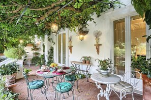 Une terrasse avec des tables et des chaises rondes, entourée de plantes en pot et de suspensions florales.