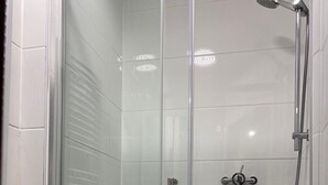 A glass-enclosed shower stall with a handheld showerhead and a handheld faucet. - Eurostar Private Flat Sleeps up to 4 London (London)