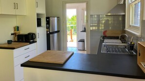 Een moderne keuken met witte kasten, een roestvrijstalen koelkast, een magnetron en een houten aanrecht.