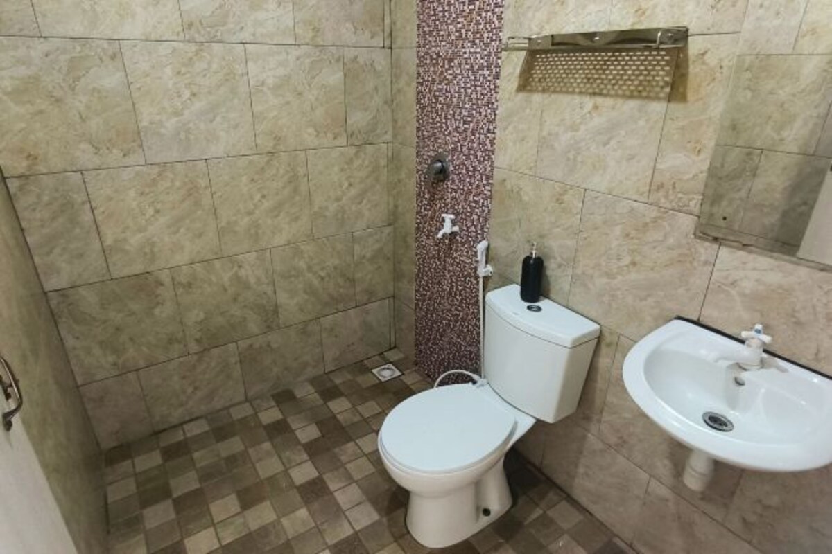 Et badeværelse med toilet, vask og bruseområde.