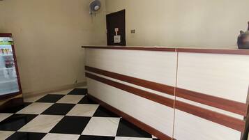 Un mostrador de recepción con piso a cuadros, un ventilador de pared y una puerta con un letrero.