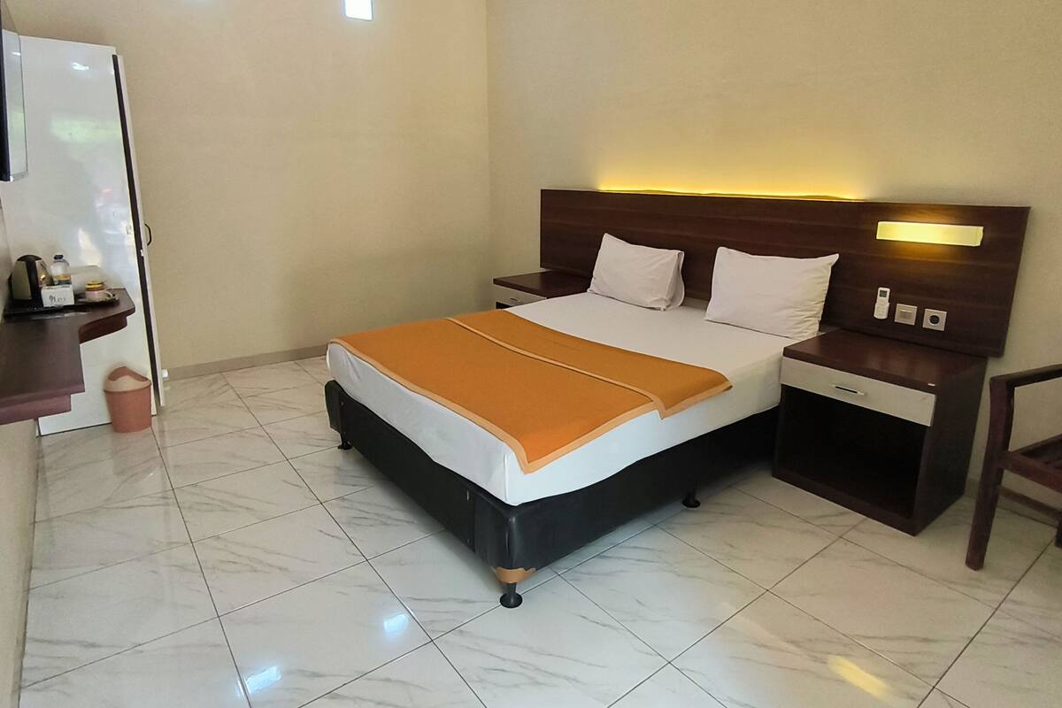 Una habitación de hotel con una cama, mesitas de noche, un escritorio y una silla.