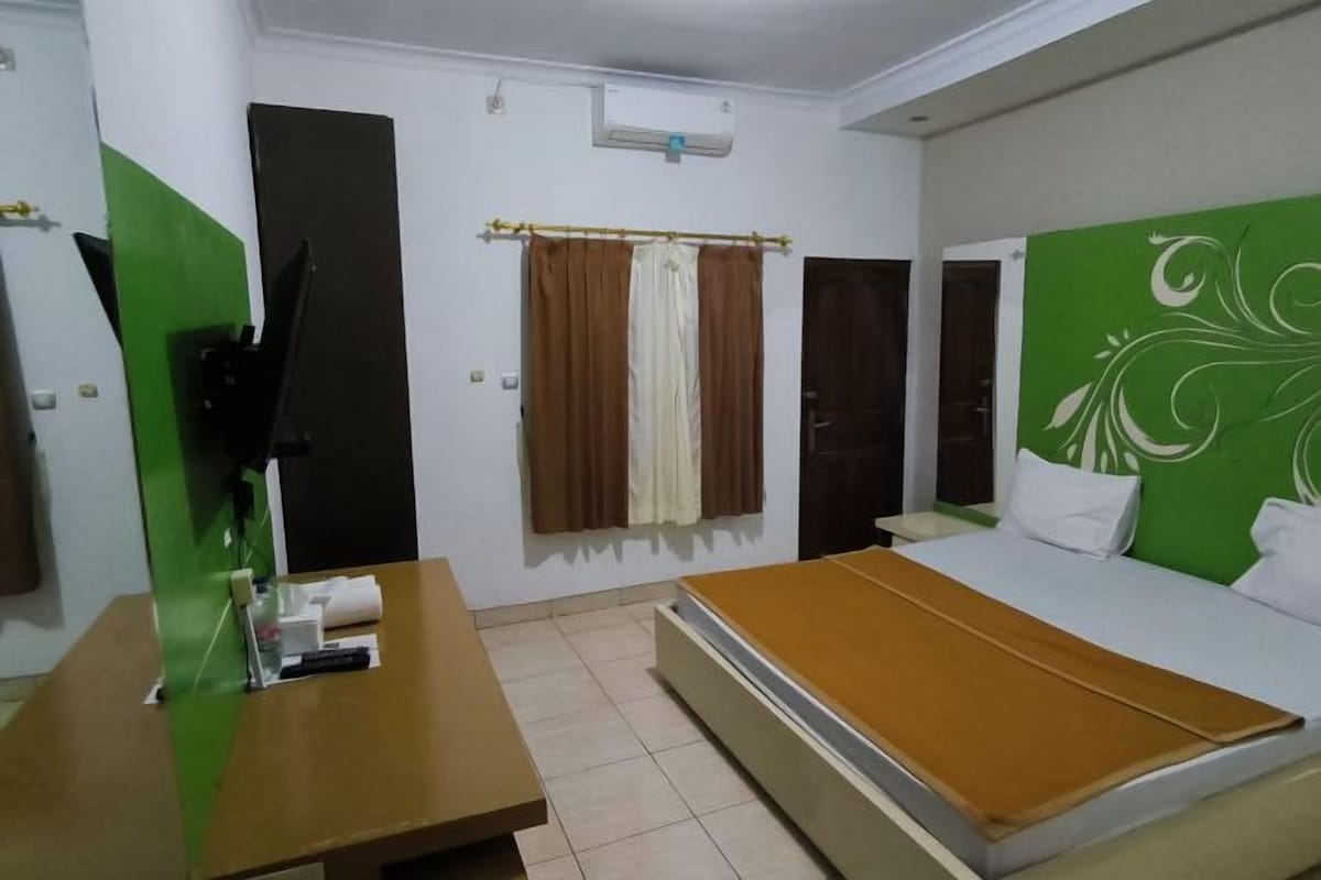 Une chambre d’hôtel avec un lit, un bureau, une télévision et une fenêtre avec des rideaux.