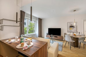 A modern hotel room with a dining area, a flat-screen TV, and a view of the outdoors. - Novos Contrada 5 204, Lugano, Switzerland (Lugano)
