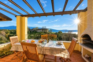 Una terrazza con un tavolo apparecchiato per la cena, affacciata su un paesaggio montuoso.