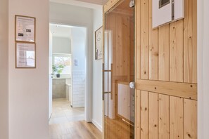 A hallway leading to a kitchen with wooden walls and a white tiled backsplash.