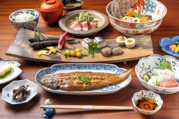 Variedad de platos japoneses, como sushi, sashimi y verduras encurtidas, sobre una mesa de madera.