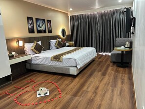 Ein modernes Hotelzimmer mit einem großen Bett, einem Nachttisch, einem Schreibtisch, einem Stuhl, einem Spiegel und einem Vorhang.