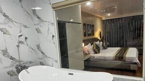 Un baño moderno con una bañera independiente, paredes de mármol y un espejo grande.