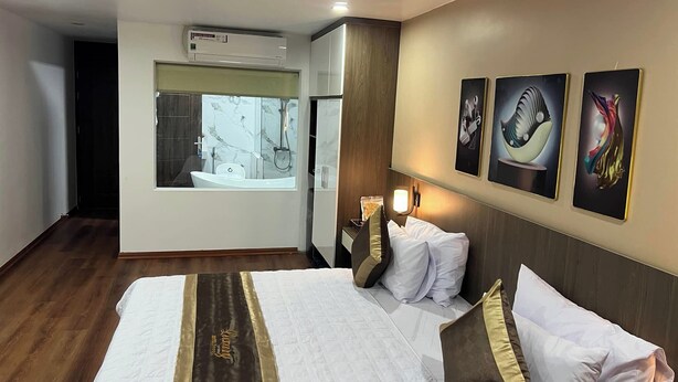 Habitación de hotel con una cama grande, baño con bañera y aire acondicionado de pared.