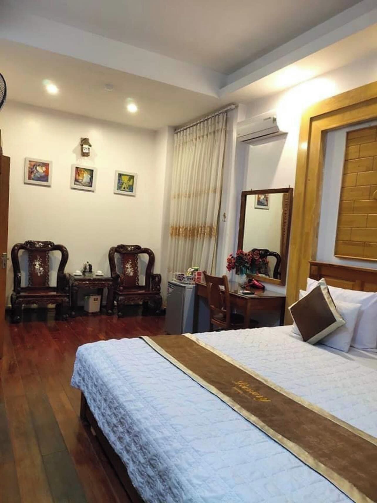 A hotel room with a bed, two chairs, a desk, and a mirror.
