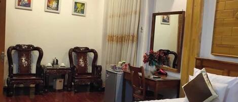 A hotel room with a bed, two chairs, a desk, and a mirror.