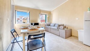 Ett kompakt bostadsutrymme med ett matbord, stolar, en soffa och ett litet kök.