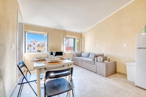 Un espacio habitable compacto con una mesa de comedor, sillas, un sofá y una pequeña kitchenette.