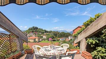 Una terrazza con un tavolo apparecchiato per mangiare, con vista su un borgo collinare.