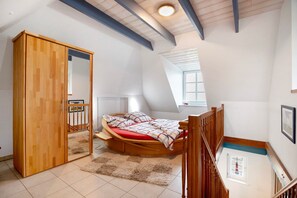 Een slaapkamer met een hoogslaper, een houten garderobe en een klein raam.