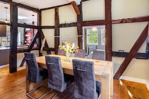 A dining area with a wooden table, grey upholstered chairs, and a vase with flowers.