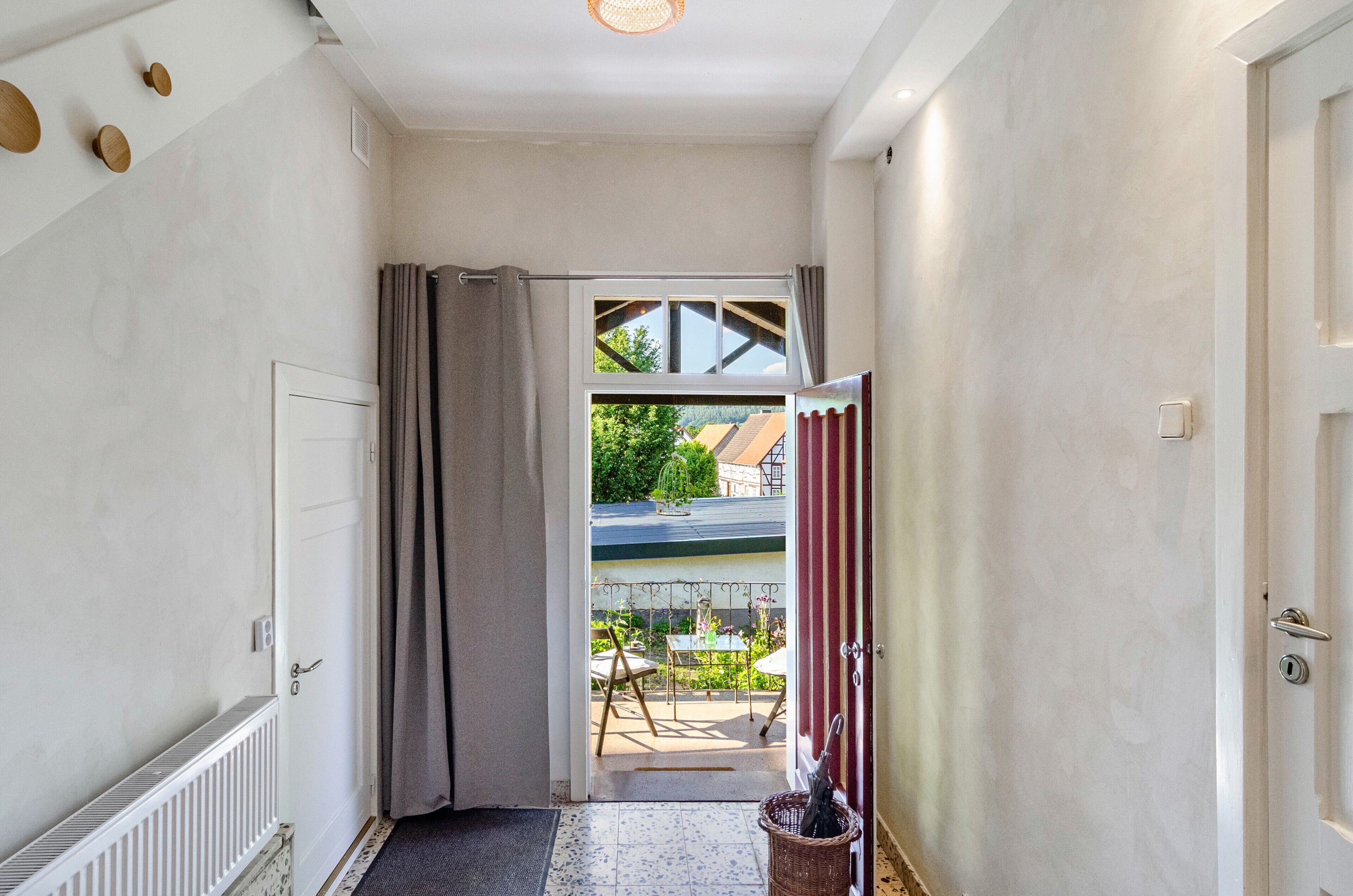 Un couloir menant à un balcon d’où l’on peut admirer un jardin et un bâtiment.