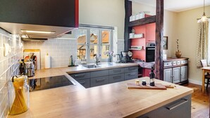 Une cuisine moderne dotée d’un îlot central, d’appareils électroménagers intégrés et offrant une vue sur l’extérieur.