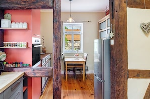 A kitchen with wooden beams, a dining table, and a refrigerator.