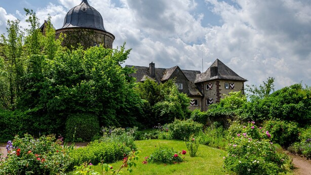 Un bâtiment historique doté d’un dôme imposant et d’un jardin où poussent différentes espèces de fleurs.