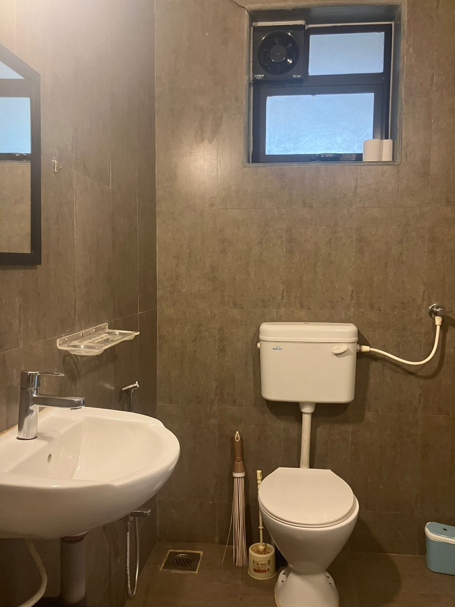 A bathroom with a sink, toilet, and a small window.