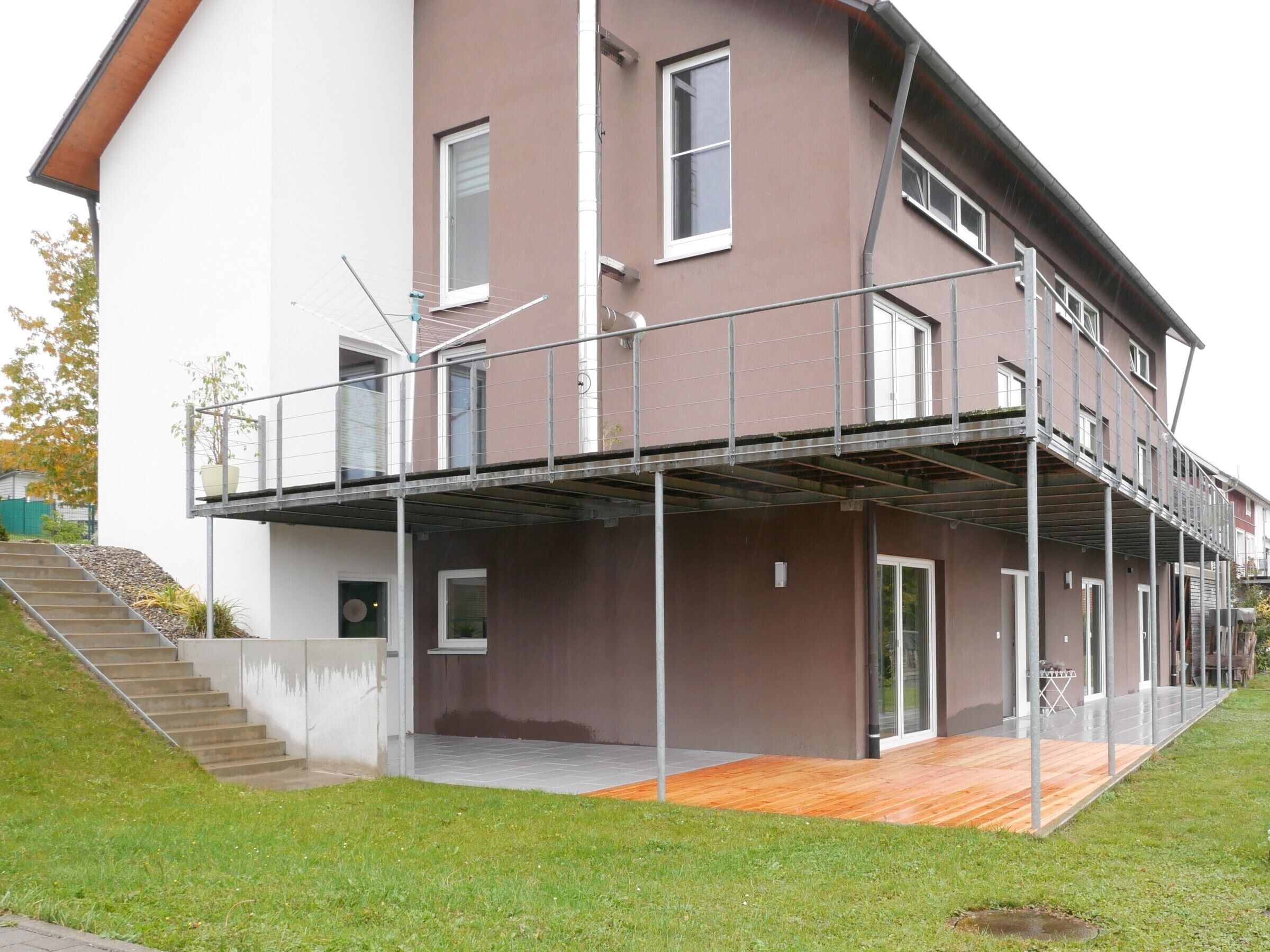 A multi-story residential building with a balcony, stairs, and a wooden deck.